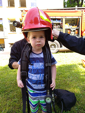 Chłopczyk przymierza plecak i hełm strażacki