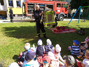 Pan strażak pokazuje dzieciom ubiór strażacki