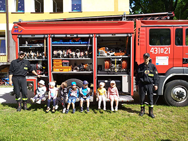 Dzieci z grupy Pszczółki razem ze strażakami przy wozie strażackim