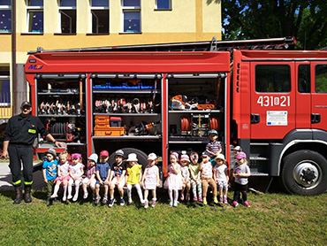 Dzieci z grypy Żabki stoją przy wozie strażackim