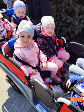 Na zdjęciu widać uśmiechnięte dzieci w wózku przy Urzędzie Miasta Hajnówka.
