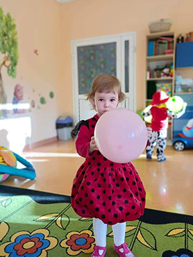 Dziewczynka przebranka za biedronkę trzyma balonik.