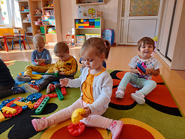 Zdjęcie przedstawia dzieci bawiące się na dywanie.