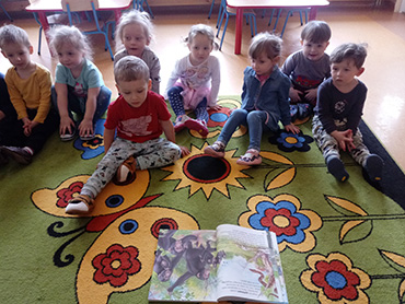 Dzieci oglądają ilustrację, na której pokazane są małpy.