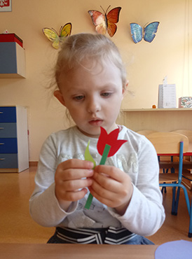 Dziewczynka trzyma sklejonego papierowego tulipana.