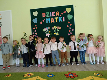 Dzieci stoją i trzymają w rękach kolorowe róże