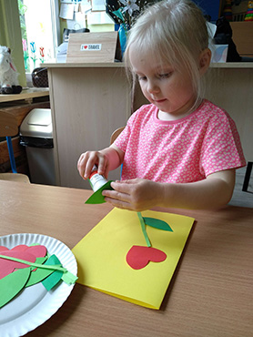 Dziewczynka przykleja zielony listek