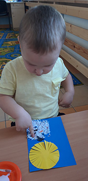 Chłopiec robi  bałwanka ze ścinek papieru.