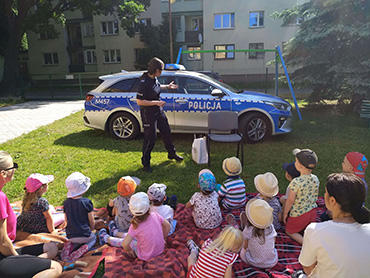 Pani policjantka pokazuje dzieciom radiowóz policyjny