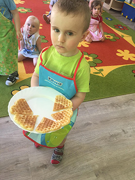 Chłopczyk trzyma talerz z goframi w kształcie serduszek