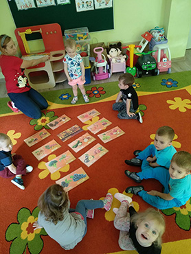Dzieci oglądają na dywanie plansze z darami jesieni