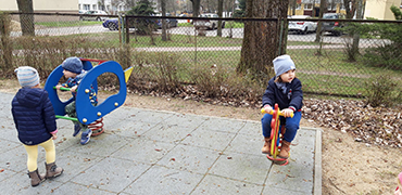 Trzecie zdjęcie przedstawia trójkę dzieci bawiące się na placu zabaw.