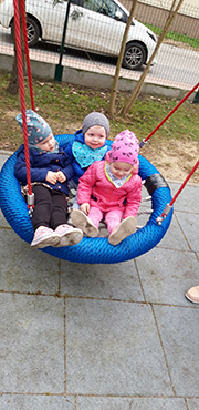Zdjęcie przedstawia trójkę dzieci na huśtawce w tzw. 